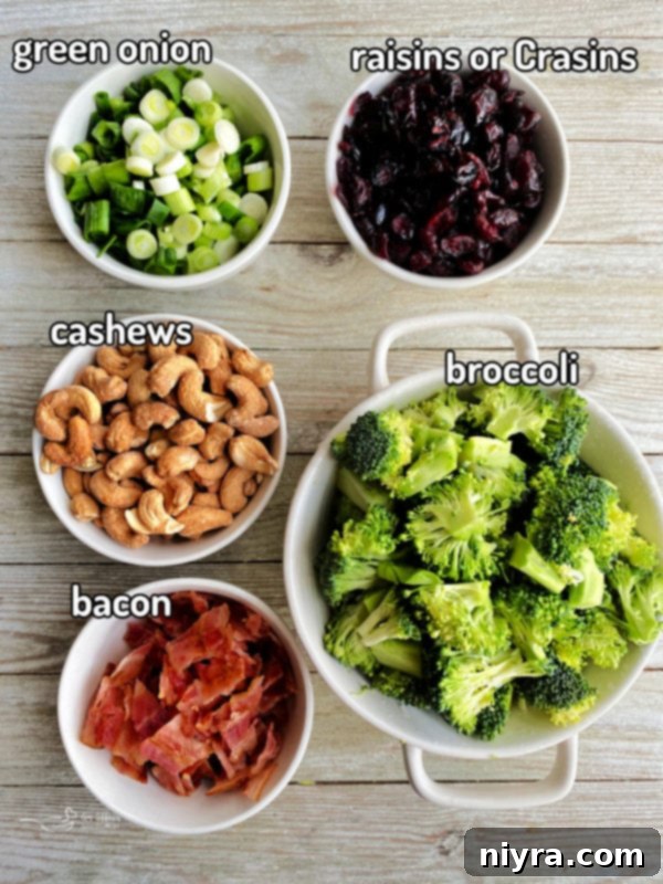 Wooden surface with cashews, green onion, raisins, broccoli, and bacon