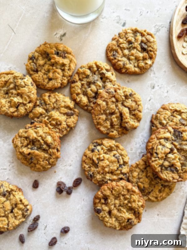 A stack of golden-brown oatmeal raisin cookies next to a glass of milk, a classic pairing.