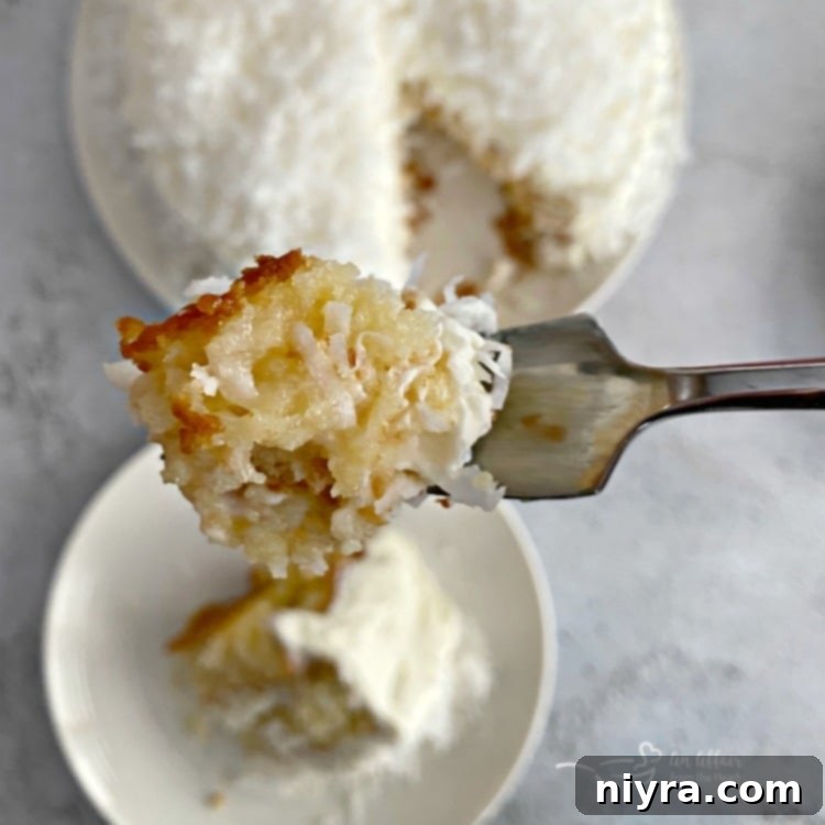 A close-up of a bite taken from a slice of Coconut Cream Poke Cake.