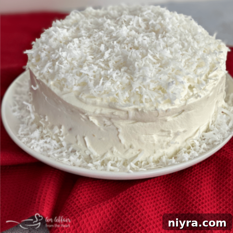 A full, beautifully frosted Coconut Cream Poke Cake on a cake stand.