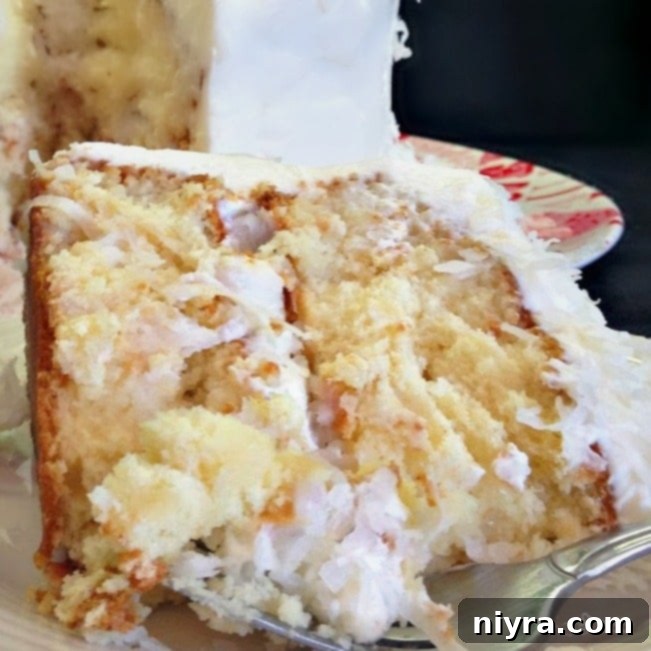 A close-up slice of Coconut Cream Poke Cake revealing its moist texture and rich frosting.