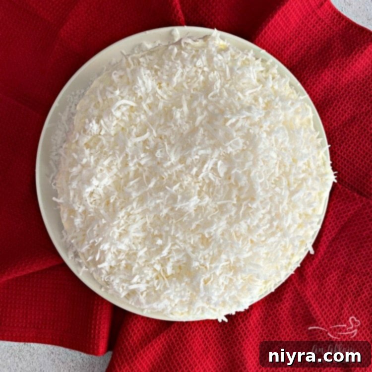 Full Coconut Cream Poke Cake with Coconut Whipped Cream Frosting, ready to be served.