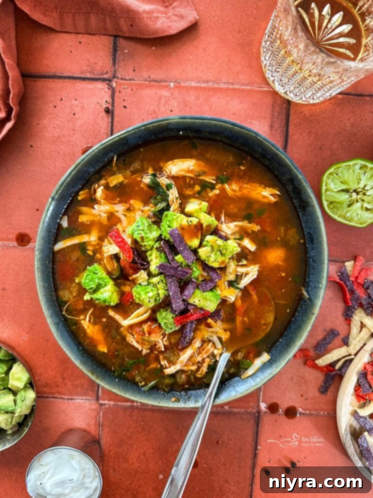 Ultimate Slow Cooker Chicken Enchilada Soup 2 A bowl of Slow Cooker Chicken Enchilada Soup garnished with cilantro and sour cream.