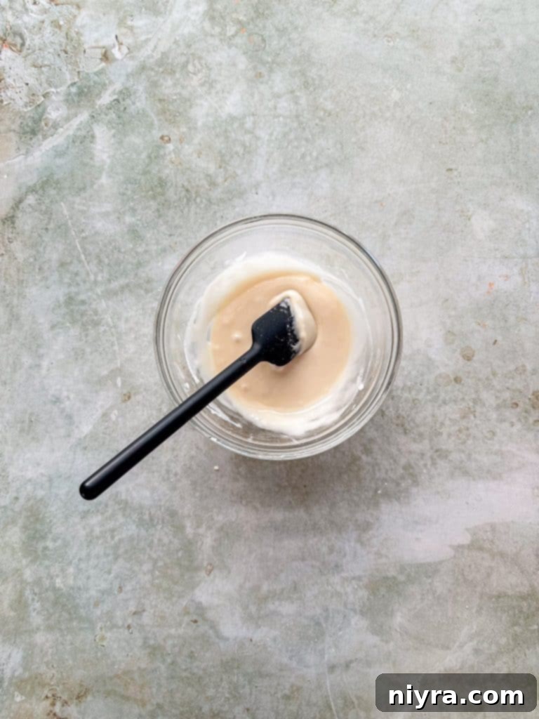Preparing the vanilla glaze in a bowl, showing powdered sugar, milk, and vanilla