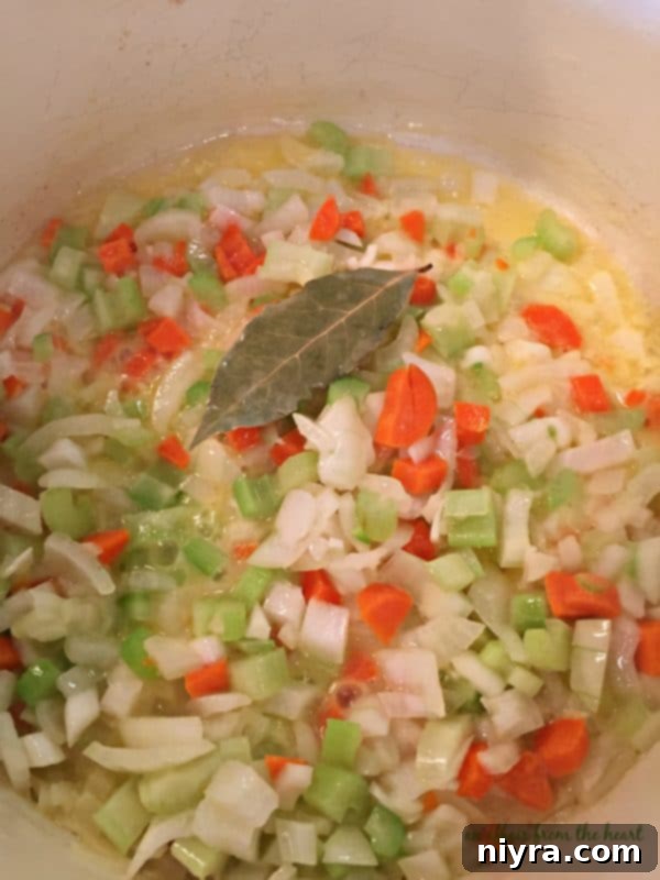 Sautéing carrots, celery, and onions in butter with a bay leaf
