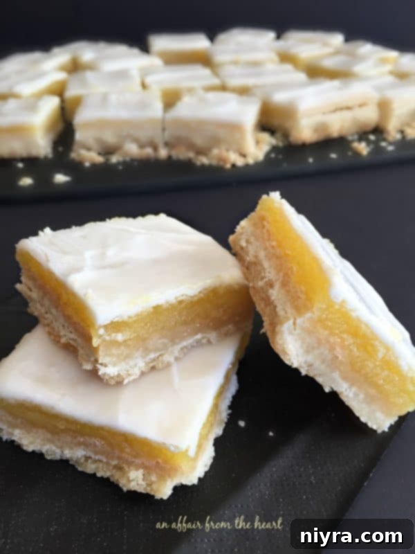Tangy Lemon Delights 2 Glazed Lemon Bars stacked neatly on a plate, ready to be served.