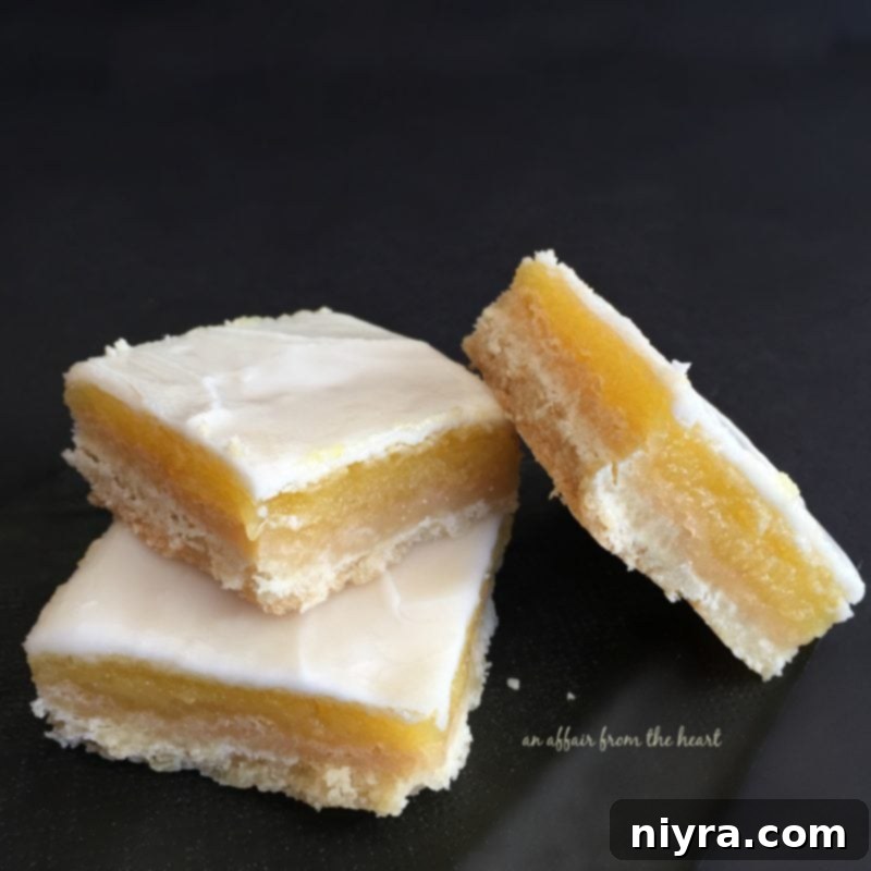 Tangy Lemon Delights 7 Glazed Lemon Bars with a smooth, shiny glaze, beautifully arranged on a white serving dish.