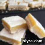 Tangy Lemon Delights 10 Glazed Lemon Bars stacked on a black napkin