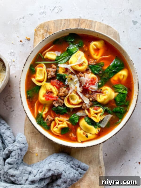 A bowl of Tortellini Soup with Sausage and Spinach, garnished with fresh parsley.