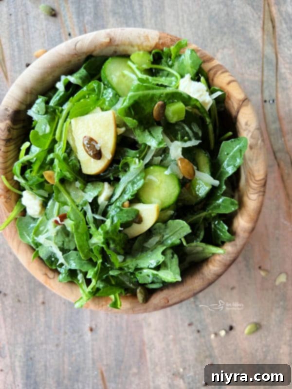 A large wooden bowl filled with the TikTok Sauerkraut Arugula Salad, showcasing the fresh ingredients.