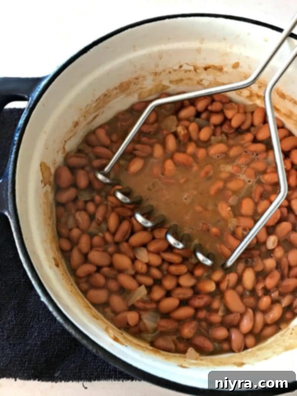 Pinto beans and beef stock simmering together in a Dutch oven on the stove