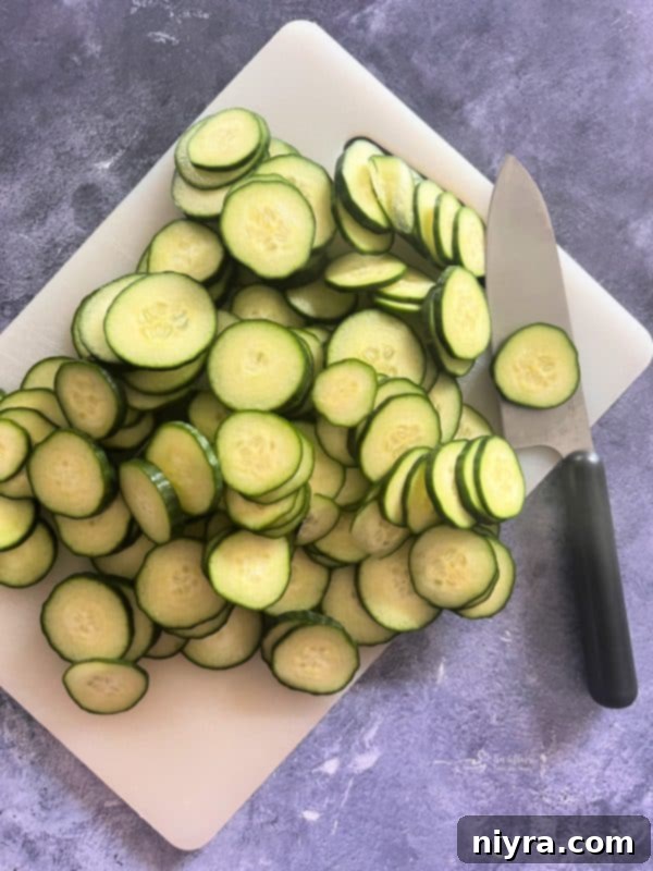 Close-up of sliced English cucumbers and sweet onions in a mason jar, ready for pickling