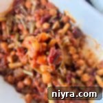 Five beans swirled together with cream cheese, Rotel and lots of cheese, baked up until hot and bubbly. Top with tomatoes and green onions before serving this Hot Taco Five Bean Dip with tortilla chips.