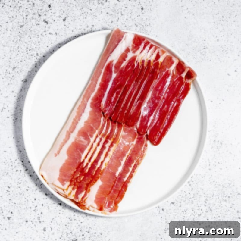 Raw bacon slices arranged in an air fryer basket