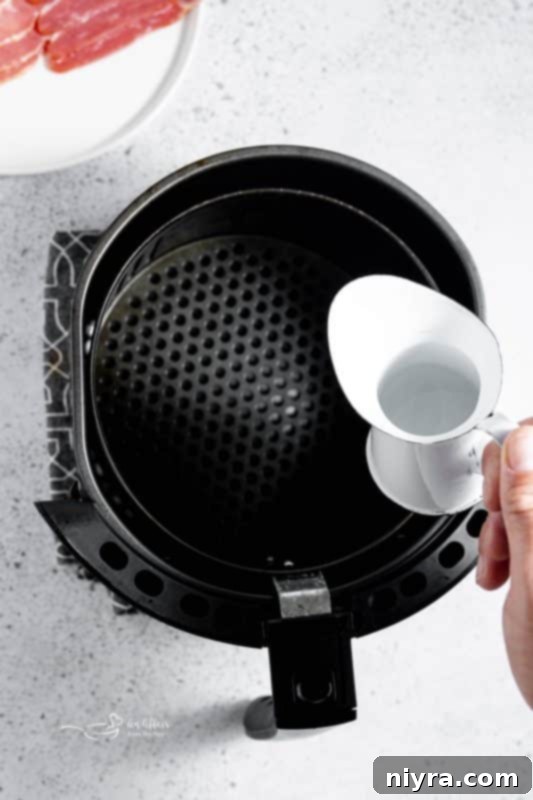 Air fryer basket preheated with a splash of water