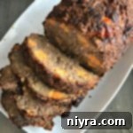 Overhead of Pork Sausage Meatloaf sliced on a white serving platter