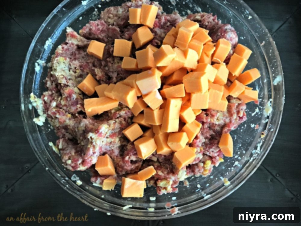 Cubed Velveeta cheese being gently added to the meatloaf mixture