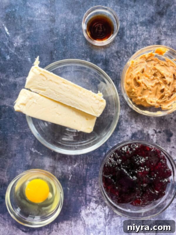 Ingredients for PB&J Oatmeal Cookie Bars laid out: butter, brown sugar, eggs, vanilla, flour, oats, baking soda, peanut butter, grape jelly