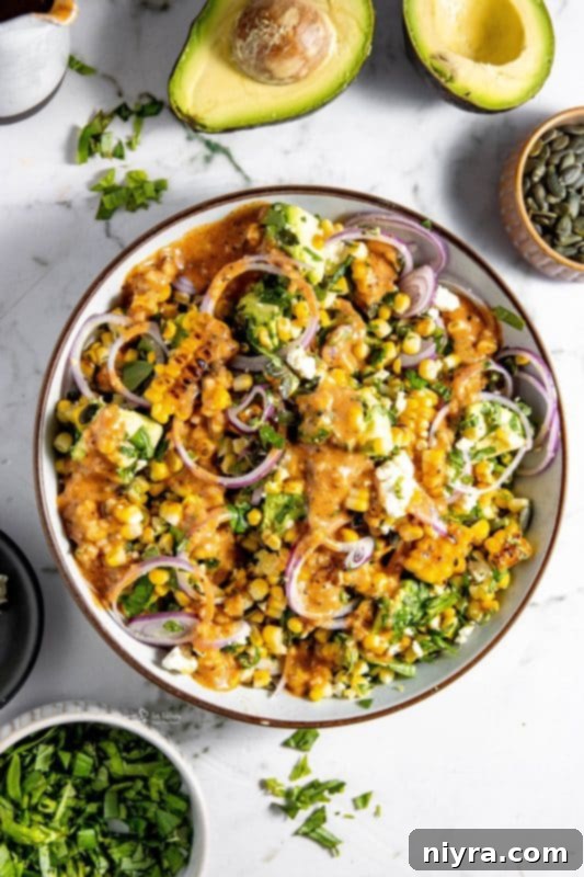 Close-up of a vibrant Grilled Corn and Avocado Salad in a white serving bowl, showcasing fresh ingredients and crumbled feta