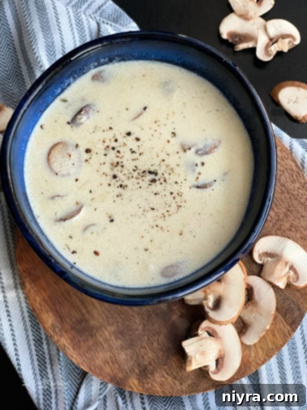A rustic blue bowl filled with rich, homemade cream of mushroom soup, garnished with fresh herbs.