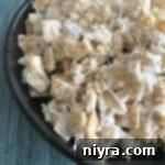 Coconut Muddy Buddies in a dark colored bowl