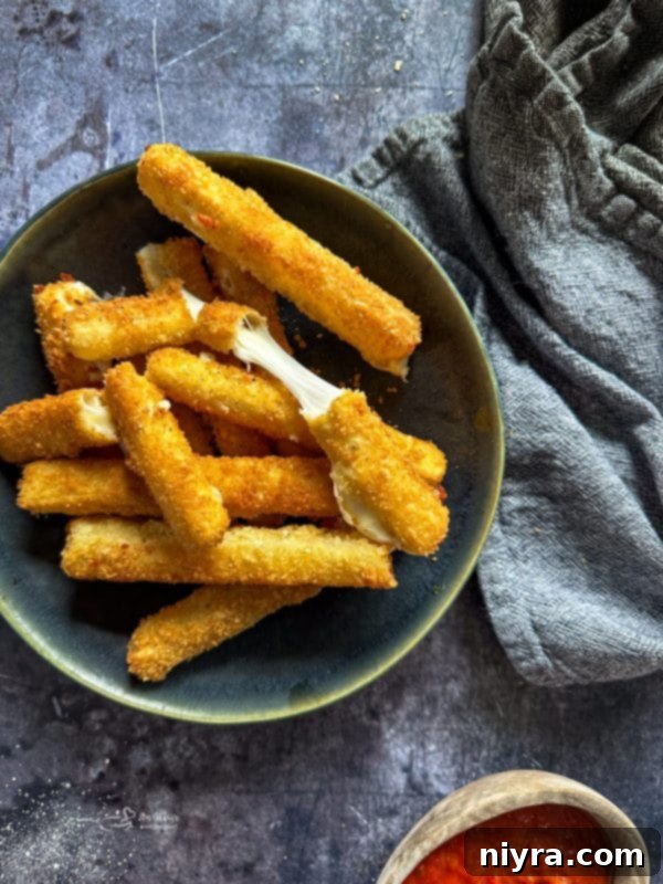 Crispy Homemade Mozzarella Sticks stacked on a green plate, ready to be served as an appetizer.