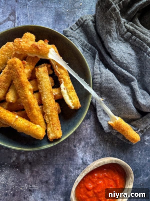 Close-up of golden brown mozzarella sticks arranged artfully, showcasing their crispy texture.