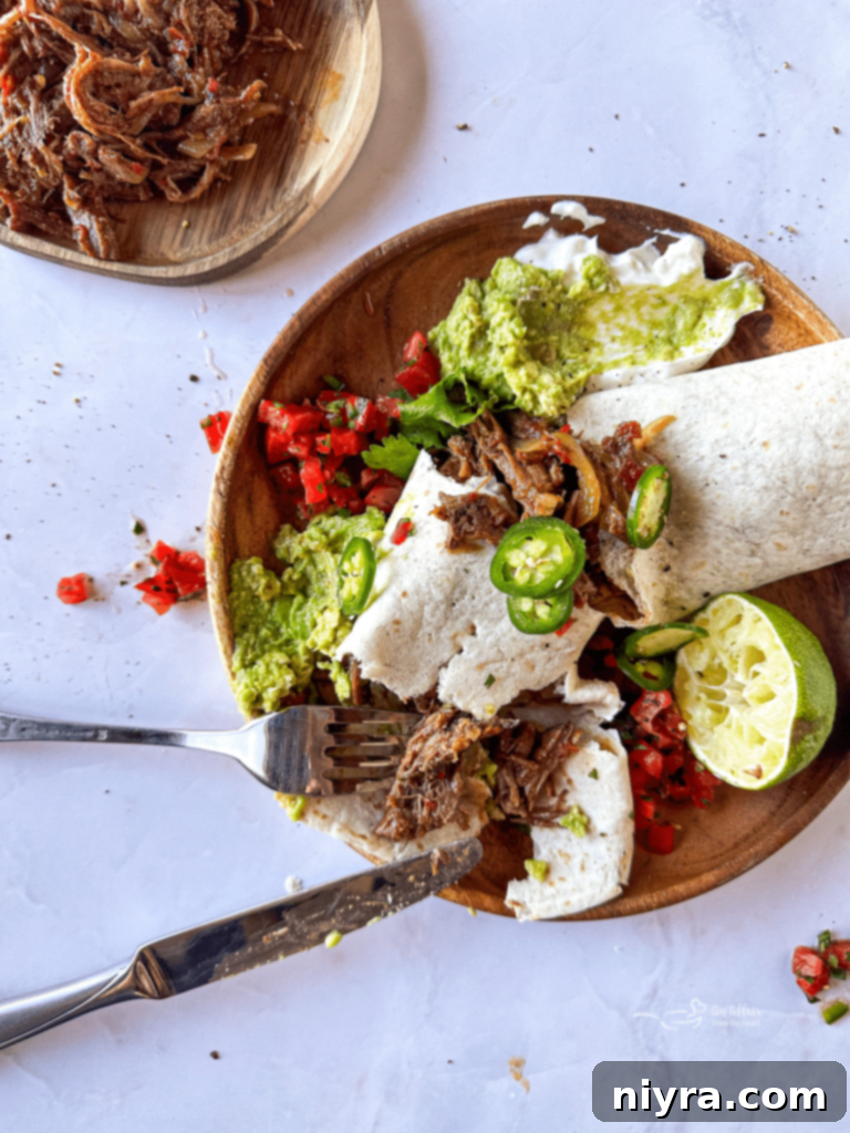 Close-up of a slow cooker shredded beef burrito cut in half, showcasing the filling.