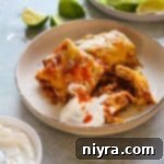 Slow Cooker Smothered Burritos and sour cream on a plate.