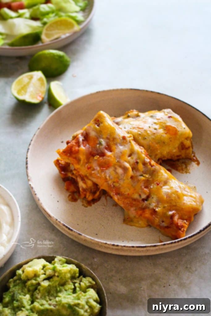 Frozen burritos layered in a slow cooker, ready to be smothered in sauce.