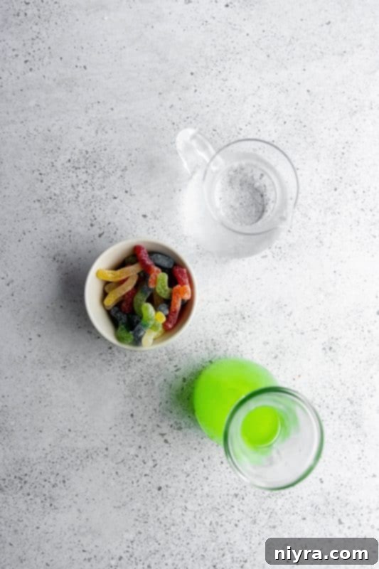 Green Halloween Kids Punch being poured into a clear glass, showing the vibrant color and floating sour worms.