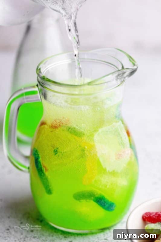 Step 4: Pouring Sprite into the pitcher with Gatorade, ice, and sour worms.