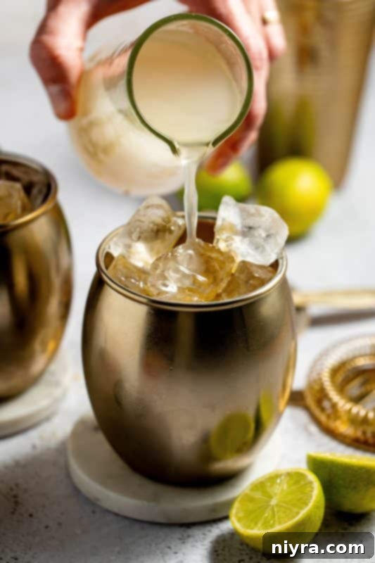 Topping the cocktail with ginger beer.