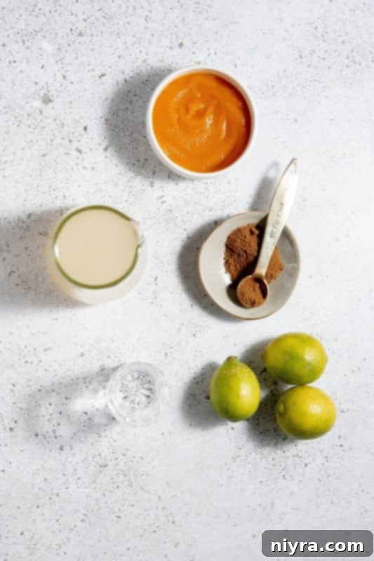 Two Pumpkin Spice Moscow Mules in copper mugs, garnished with cinnamon sticks and a small pumpkin.