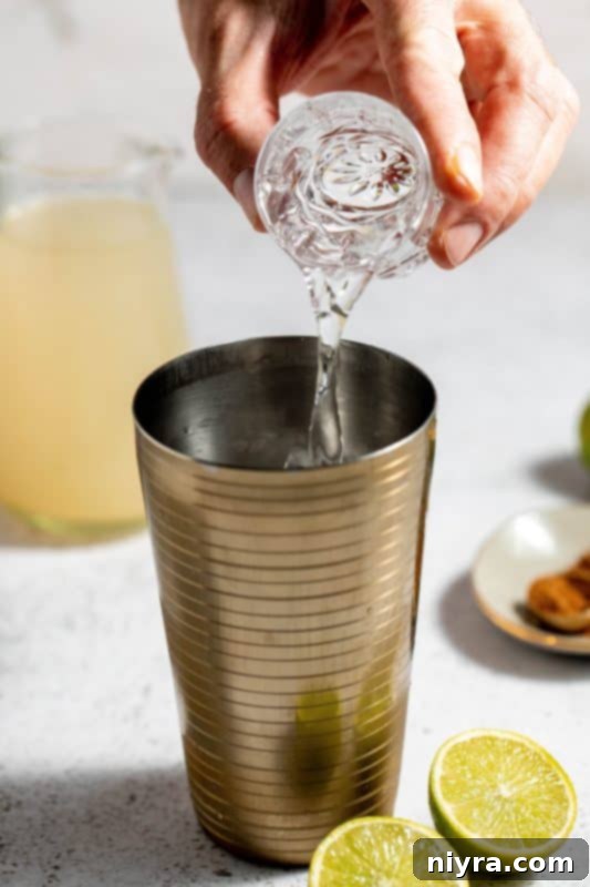 Pouring vodka into a cocktail shaker with ice.