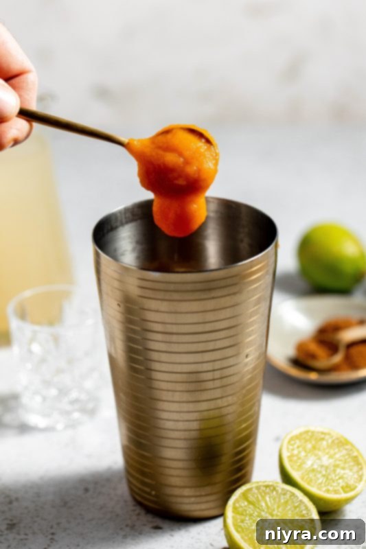 Adding pumpkin puree to the cocktail shaker.