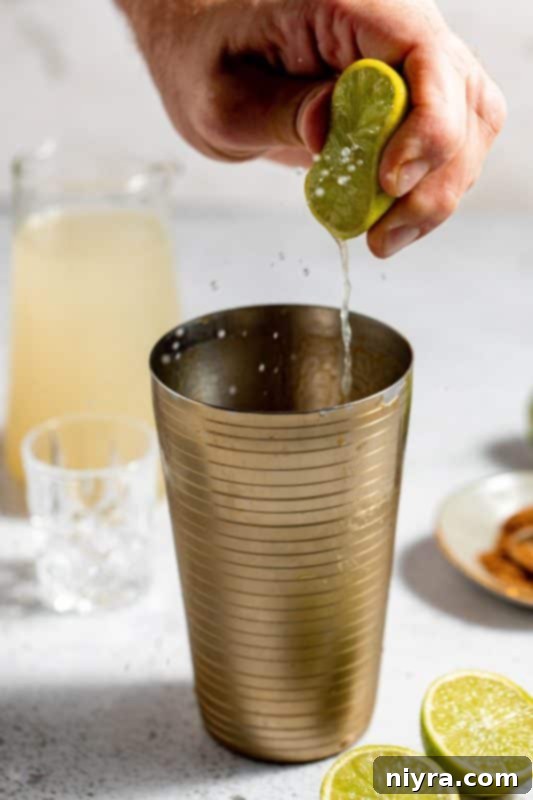 Squeezing lime juice into the cocktail shaker.