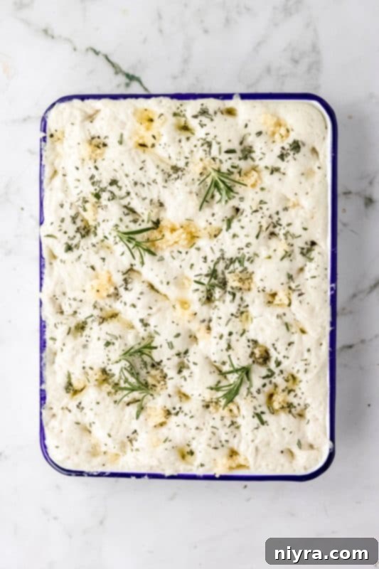Focaccia dough topped with minced garlic and fresh rosemary before baking