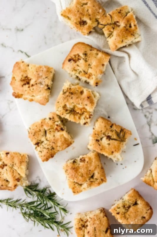 A perfectly baked square of Garlic Rosemary Focaccia Bread on a cutting board