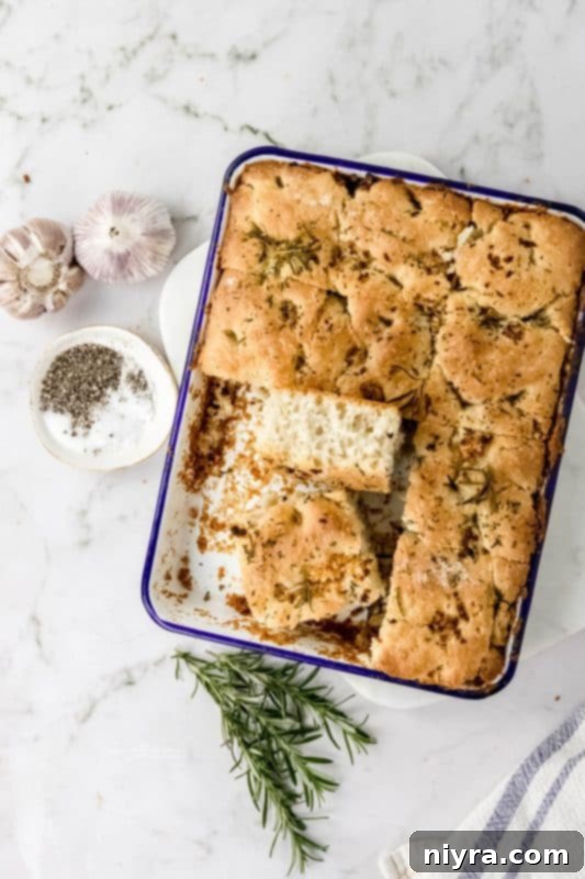 A whole pan of golden-brown Garlic Rosemary Focaccia Bread, ready to be sliced