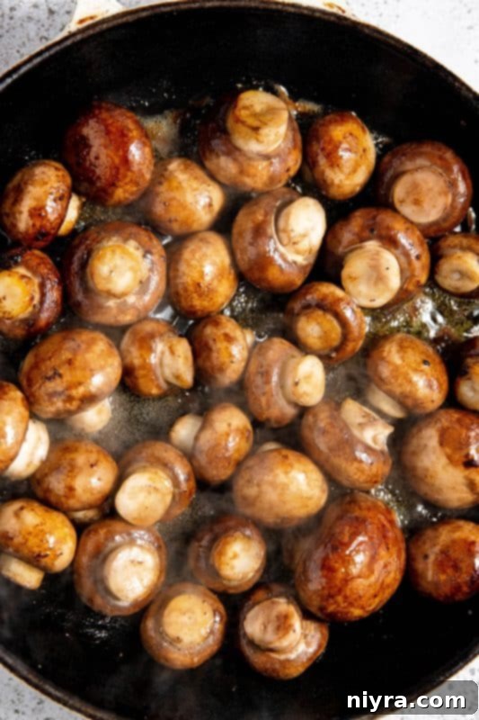 White wine added to sautéed mushrooms in a skillet.