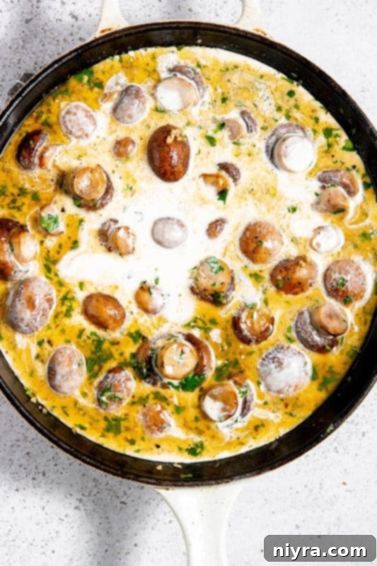 Heavy cream added to mushrooms and herbs in a skillet.