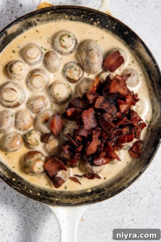 Cooked bacon added back to the creamy mushroom mixture in a skillet.