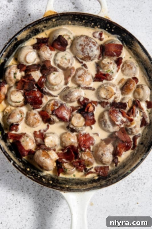 Stirring cooked bacon into the creamy mushroom mixture.