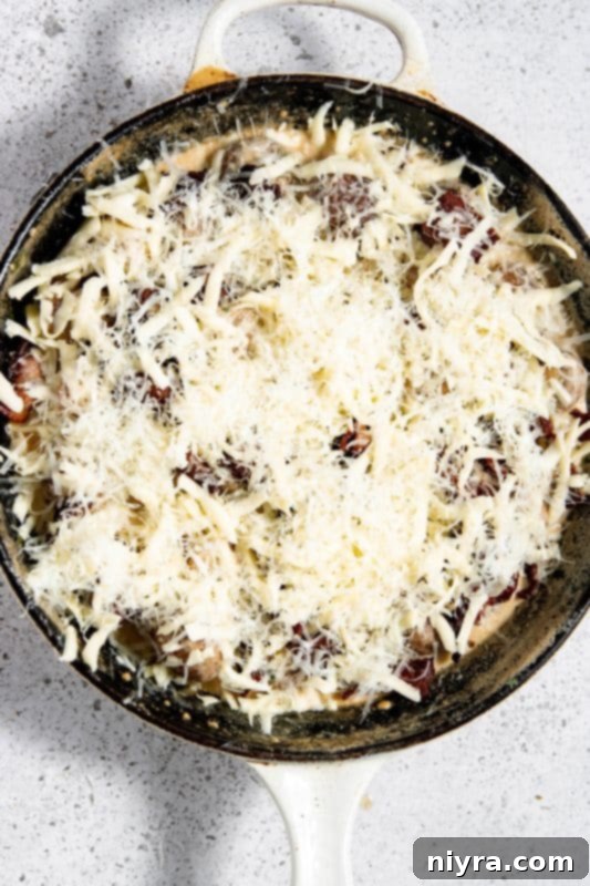 Cheese sprinkled over the creamy mushroom and bacon dish before broiling.