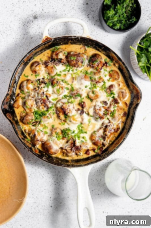 A skillet filled with creamy mushrooms and bacon, freshly cooked and steaming.