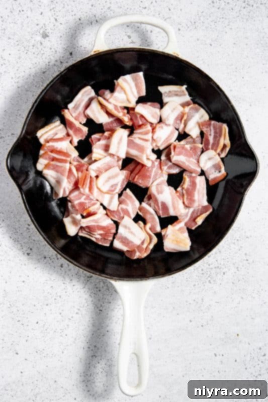Bacon cooking in a large skillet.