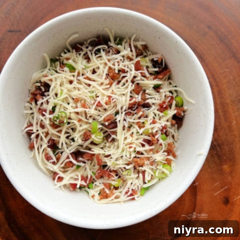 Half of the green onion, chives, bacon, and Swiss cheese in a small bowl