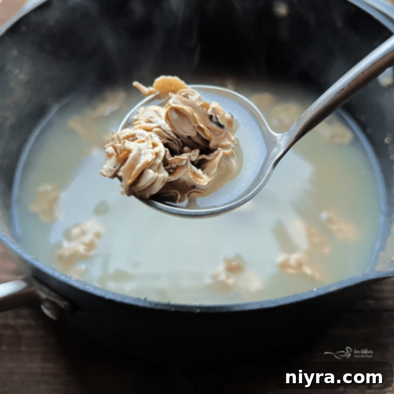 Oysters simmering in a saucepan, their edges just beginning to curl.