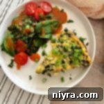 Slice of Bacon & Potato Frittata and a side salad on a white plate